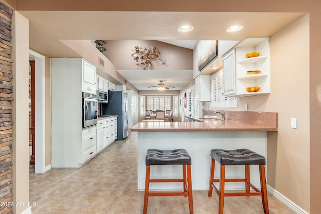 kitchen featuring sink, stainless steel appliances, kitchen peninsula, a breakfast bar, and white cabinets