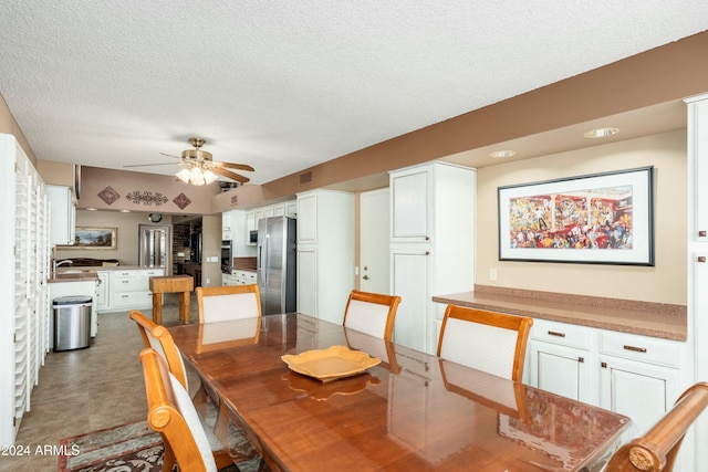 dining space featuring ceiling fan, sink, and a textured ceiling