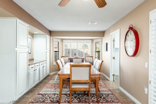 dining area featuring ceiling fan and a textured ceiling