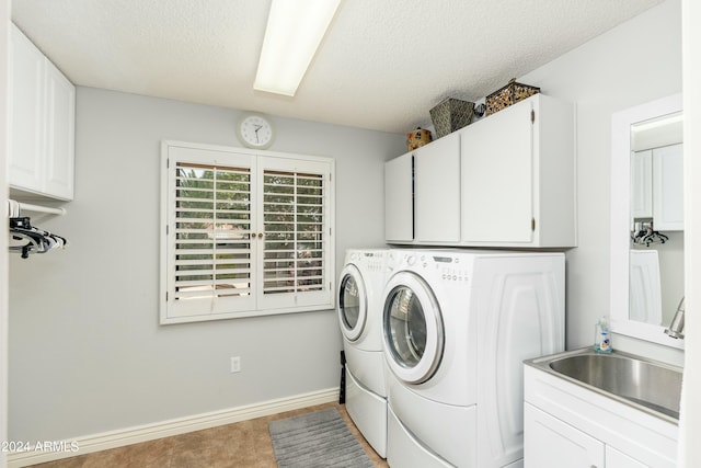 laundry room with a textured ceiling, cabinets, sink, and washing machine and clothes dryer