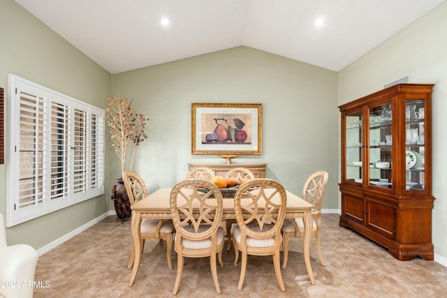 carpeted dining area with vaulted ceiling