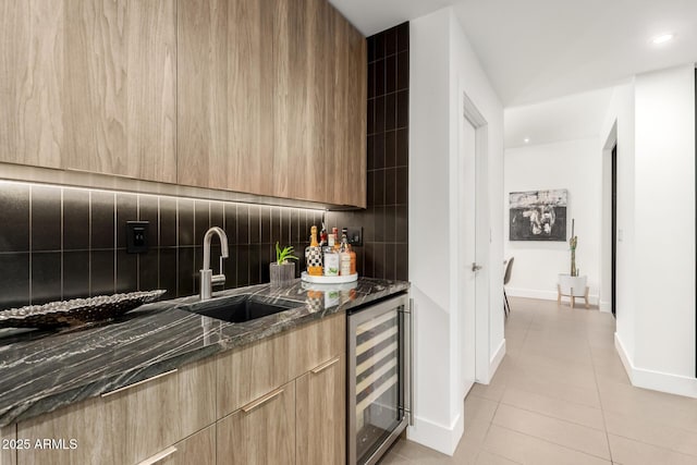 kitchen with wine cooler, modern cabinets, a sink, light brown cabinets, and decorative backsplash