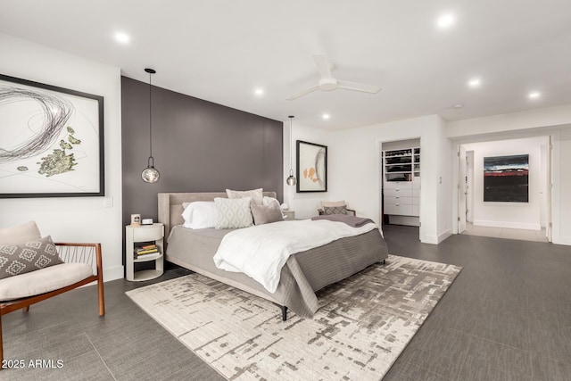 bedroom with recessed lighting, dark colored carpet, a walk in closet, baseboards, and a ceiling fan