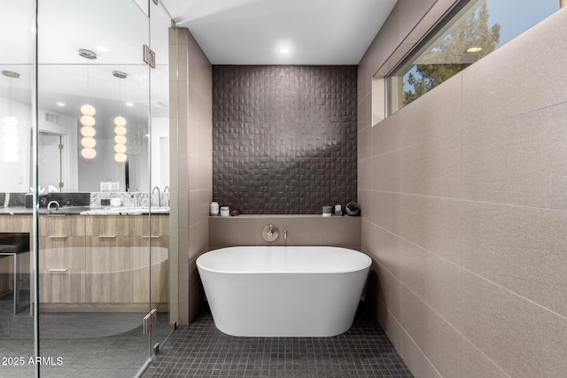 bathroom featuring a freestanding bath, tile walls, double vanity, tile patterned floors, and a stall shower