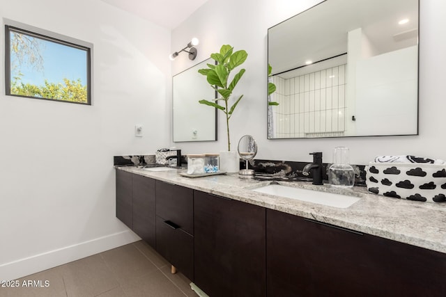 bathroom featuring baseboards, double vanity, and tile patterned flooring