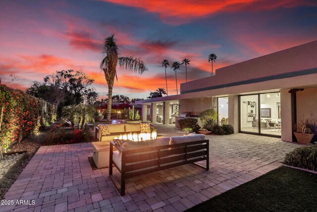 patio terrace at dusk featuring an outdoor hangout area and area for grilling