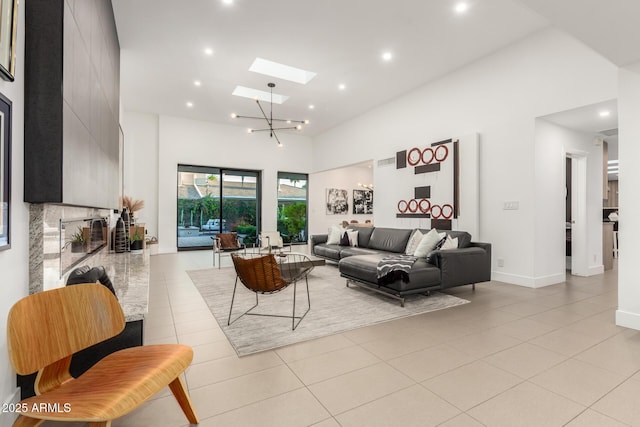 living area with a towering ceiling, light tile patterned floors, a skylight, recessed lighting, and baseboards