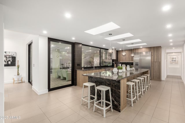 kitchen featuring built in fridge, modern cabinets, a skylight, a breakfast bar area, and recessed lighting