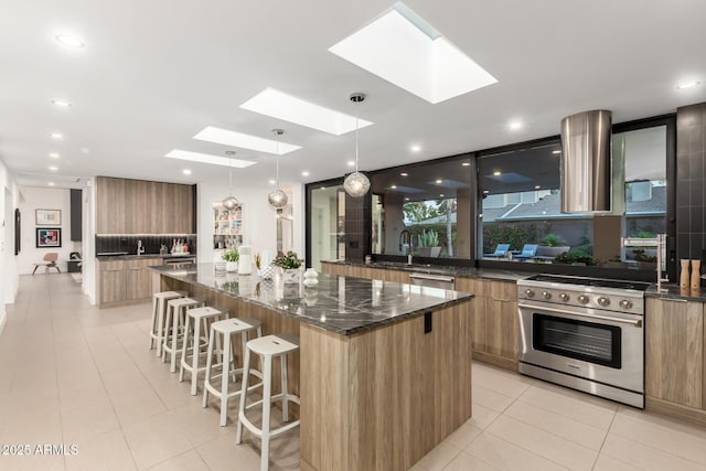 kitchen featuring stainless steel appliances, modern cabinets, a skylight, a spacious island, and dark stone counters