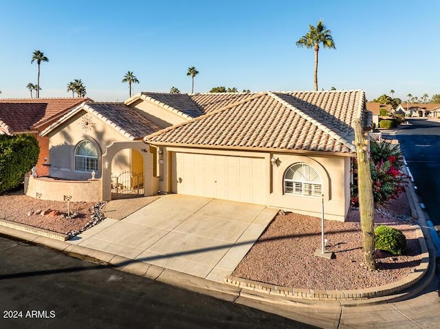 mediterranean / spanish home featuring stucco siding, concrete driveway, an attached garage, and a tile roof