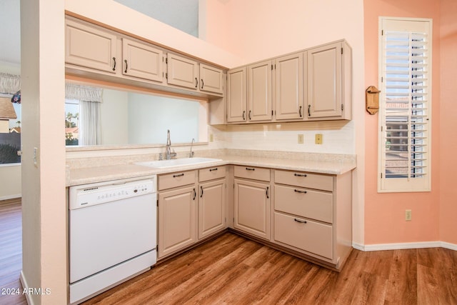 kitchen featuring a sink, white dishwasher, light wood finished floors, baseboards, and light countertops