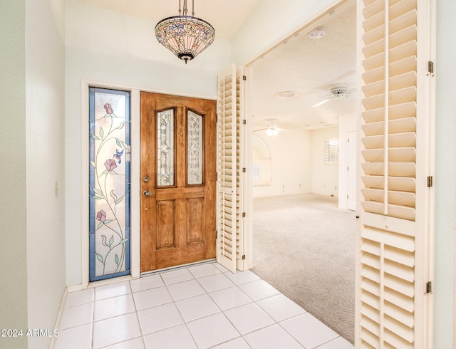 foyer entrance featuring light carpet, light tile patterned floors, baseboards, and a wealth of natural light