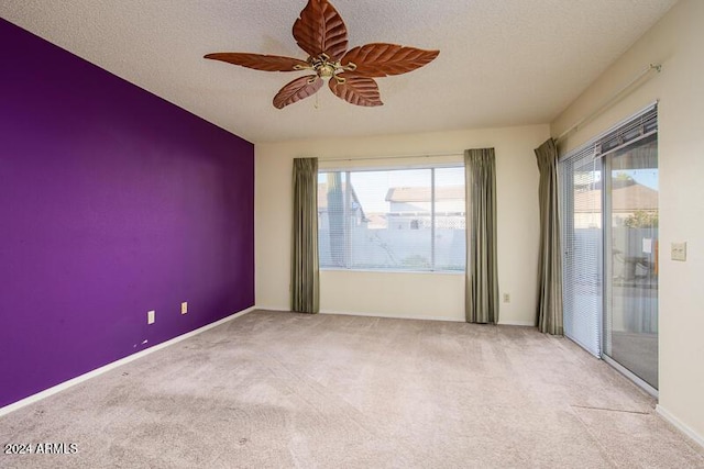 carpeted spare room with baseboards, a textured ceiling, and a ceiling fan