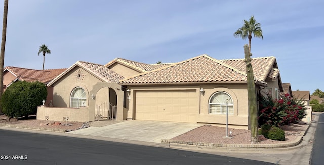 mediterranean / spanish-style home featuring stucco siding, concrete driveway, an attached garage, and a tiled roof