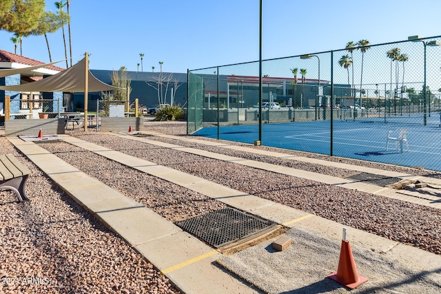 surrounding community with a tennis court and fence