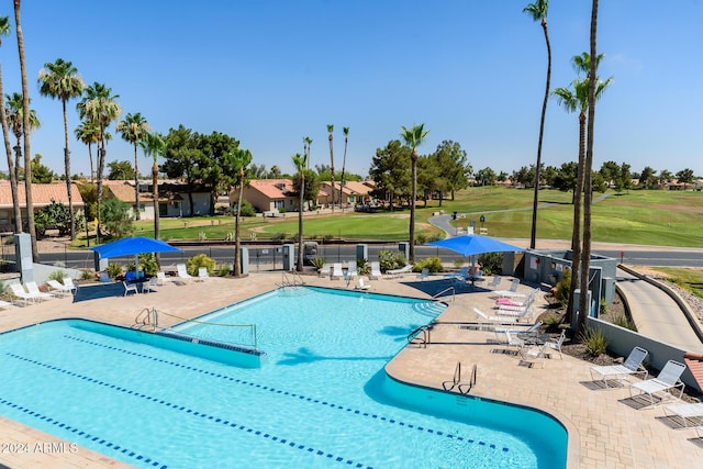 community pool featuring a patio area, a lawn, and fence