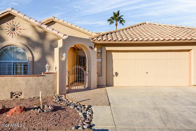 mediterranean / spanish house with a gate, an attached garage, driveway, and stucco siding