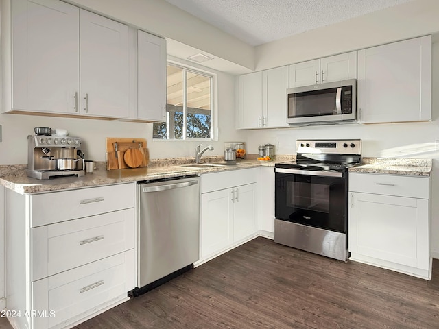 kitchen featuring white cabinetry, sink, stainless steel appliances, dark hardwood / wood-style flooring, and a textured ceiling