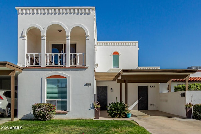 mediterranean / spanish home featuring a front lawn, a carport, and a balcony