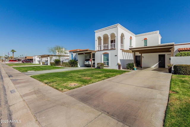 mediterranean / spanish-style house featuring a carport, a balcony, and a front lawn