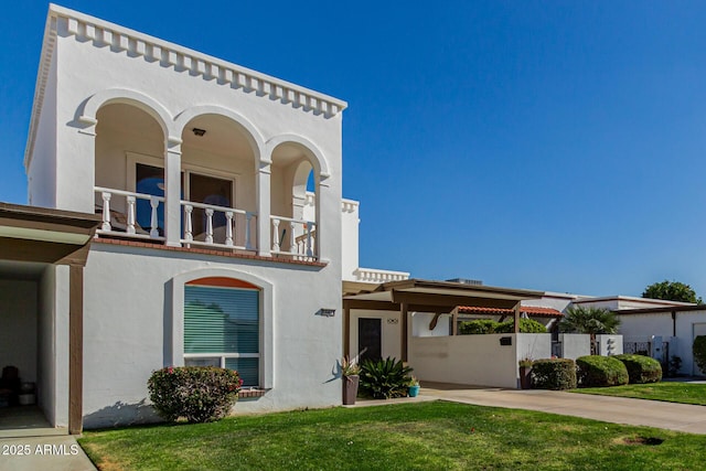 mediterranean / spanish-style house featuring a front lawn, a carport, and a balcony