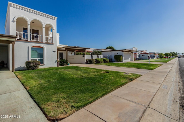 view of front of house featuring a garage, a balcony, and a front yard