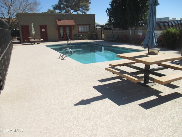 community pool with french doors, a patio, and fence