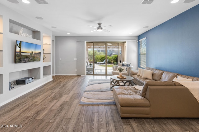 living room with hardwood / wood-style floors, built in shelves, and ceiling fan