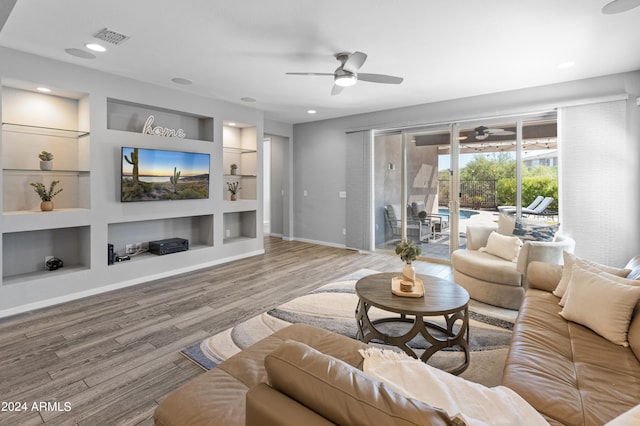 living room with hardwood / wood-style flooring, ceiling fan, and built in shelves