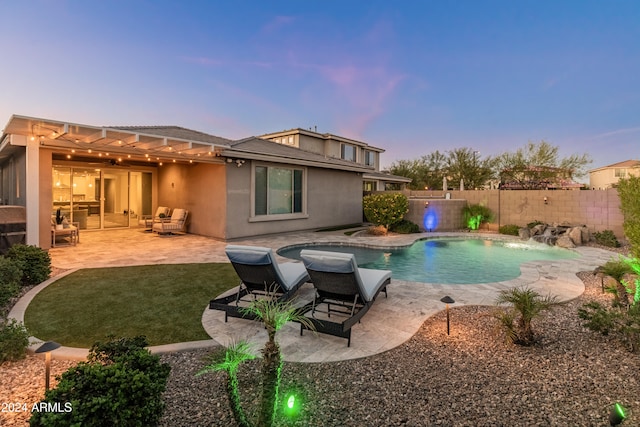 pool at dusk featuring a patio and pool water feature