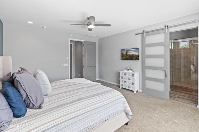 carpeted bedroom with a barn door and ceiling fan