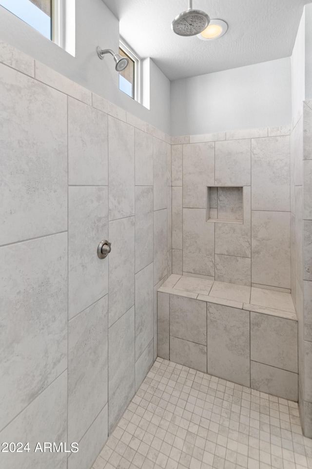 bathroom featuring a textured ceiling, plenty of natural light, and tiled shower