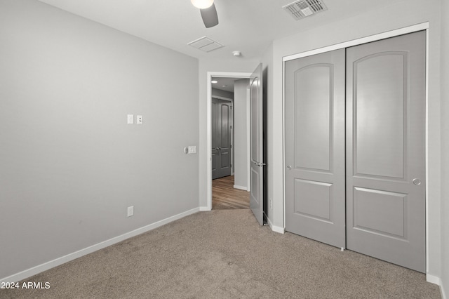 unfurnished bedroom featuring light carpet, a closet, and ceiling fan