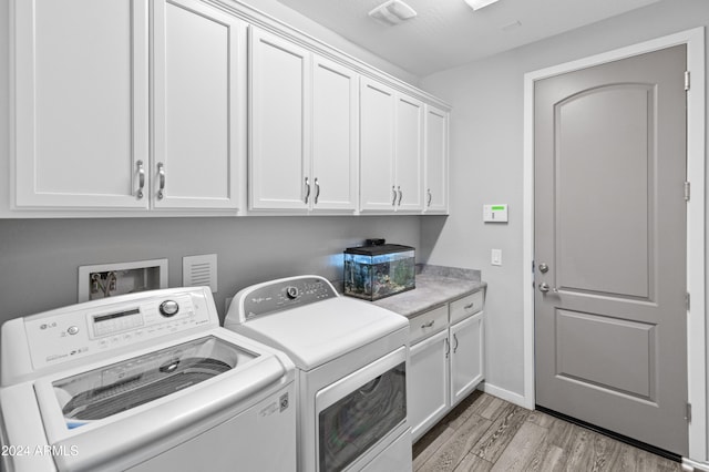 washroom featuring washing machine and dryer, light hardwood / wood-style floors, and cabinets