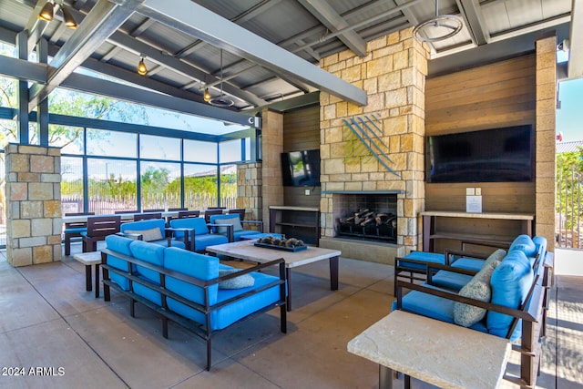 interior space featuring a towering ceiling, concrete floors, an outdoor stone fireplace, and wooden walls