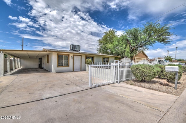 ranch-style house with an attached carport, a fenced front yard, cooling unit, driveway, and stucco siding