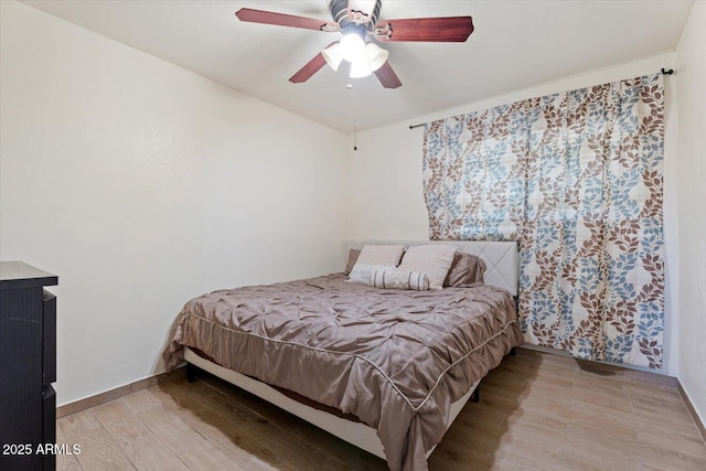 bedroom with wood finished floors, a ceiling fan, and baseboards