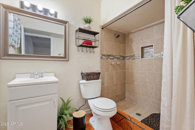 bathroom with tiled shower, vanity, and toilet