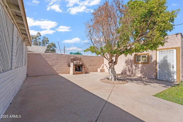 view of patio / terrace featuring an outdoor fireplace and fence