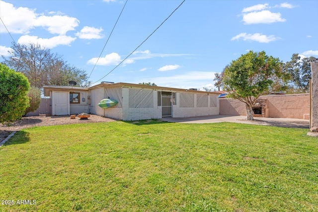 rear view of house featuring a yard, brick siding, a patio, and fence