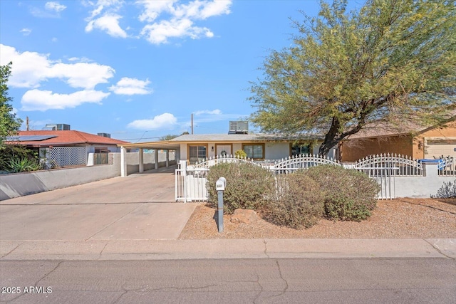 ranch-style house with a carport, a fenced front yard, a gate, and driveway