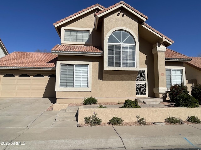 mediterranean / spanish-style house featuring a tile roof, concrete driveway, a garage, and stucco siding