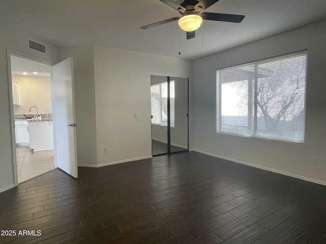 unfurnished bedroom with dark wood-style floors, visible vents, baseboards, and a sink