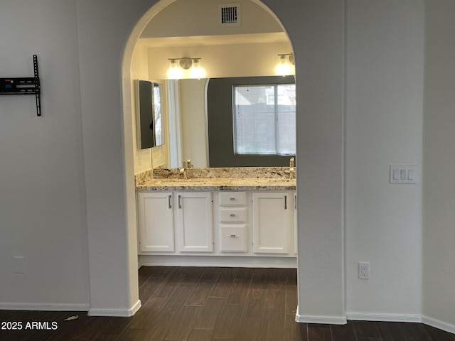 bathroom with double vanity, visible vents, baseboards, and wood tiled floor