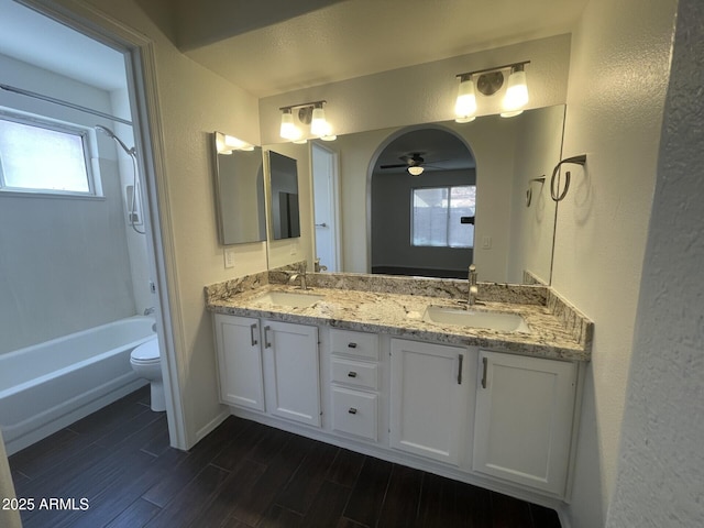 full bath featuring a sink, wood finish floors, toilet, and bathing tub / shower combination