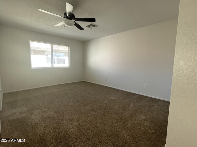 unfurnished room with dark colored carpet, visible vents, baseboards, and a ceiling fan