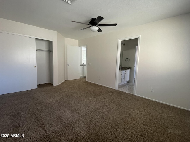 unfurnished bedroom featuring light carpet, baseboards, ensuite bathroom, and a closet