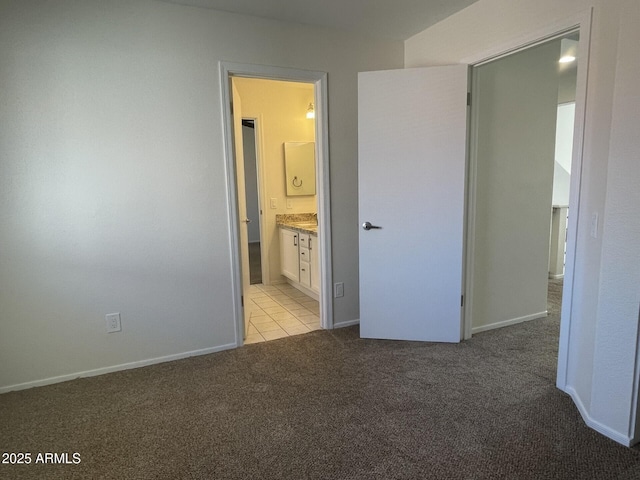 unfurnished bedroom with ensuite bath, light colored carpet, and baseboards