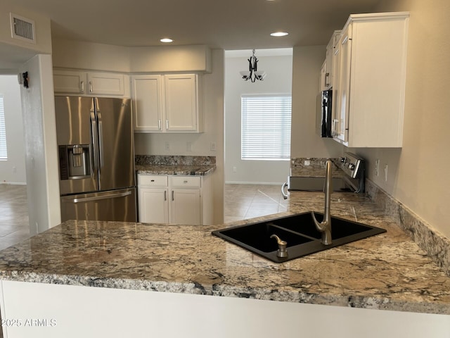 kitchen featuring white cabinets, light stone countertops, stainless steel refrigerator with ice dispenser, and a sink