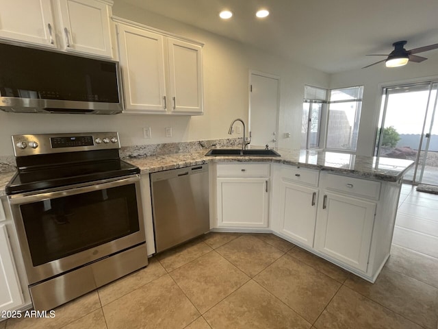 kitchen featuring recessed lighting, appliances with stainless steel finishes, a peninsula, white cabinetry, and a sink